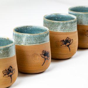 כוס קרמיקה בעבודת יד בגוון חום עם גלזורה ירקרקה וציור פרח עדין.