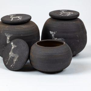 קופסאות קרמיקה בעבודת יד בגוון שחור־אפור טבעי עם מכסים מעוטרים בציור לבן של צבי ארץ ישראלי. נוצרו בסטודיו "אפרת יוצאת מהכלים" שבמושב אודם, בעיצוב טבעי עם השראה מהנוף והחי של רמת הגולן.