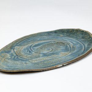 מגש קרמיקה בעבודת יד, בגוון כחול עם דוגמת ספירלה עדינה במרכז.