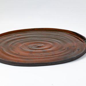 מגש קרמיקה עגול בעבודת יד של אפרת אלפסי, בגוון חום אדמתי עם טקסטורה ספירלית עדינה במרכז. פריט ייחודי בעיצוב טבעי המתאים להגשה או לעיצוב שולחן.