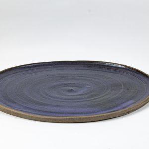 מגש קרמיקה עגול בעבודת יד של אפרת אלפסי, עם זיגוג בגוון סגול וטקסטורה מעגלית רכה. כלי קרמיקה אלגנטי בהשראת נופי הגולן, מתאים להגשה, אירוח או עיצוב שולחן.