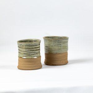 כוס קרמיקה בעבודת יד עם גלזורה ירקרקה ובסיס חום טבעי בעיצוב בהשראת נוף ההר.