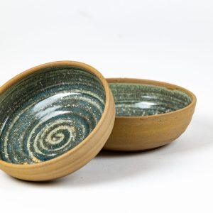 קערת קרמיקה בעבודת יד עם טקסטורה ספירלית בגוון ירוק־ים, על רקע לבן. נוצרה בסטודיו "אפרת יוצאת מהכלים" שבגולן, משלבת עיצוב אמנותי עם שימוש יומיומי באוכל והגשה.